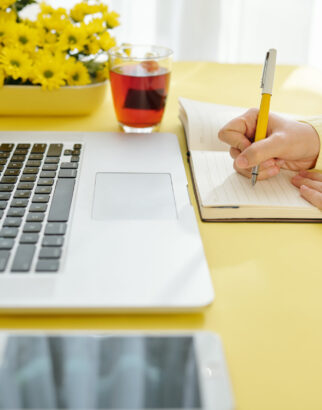 Businesswoman writing in planner Hands of businesswoman analyzing report of screen of laptop and taking notes in planner