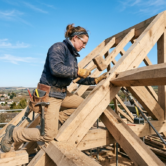 AF26_A skilled carpenter in work clothes on a wooden roof structure AF26_A skilled carpenter in work clothes on a wooden roof structure