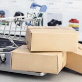Online shopping concept. Online web store purchase. Cardboard boxes and shopping cart on computer laptop Mehrere Versandkartons liegen vor einem Laptop mit geöffnetem Onlineshop, daneben steht ein kleiner Einkaufswagen. Die Szene symbolisiert Onlinebestellungen, Warenkorb, Versand und E-Commerce-Prozesse. Das Bild passt zu Themen wie Onlineshop ohne Verkäufe, Kaufabbrüche, Warenkorb-Optimierung, Versandvertrauen und bessere Shop-Conversion.
