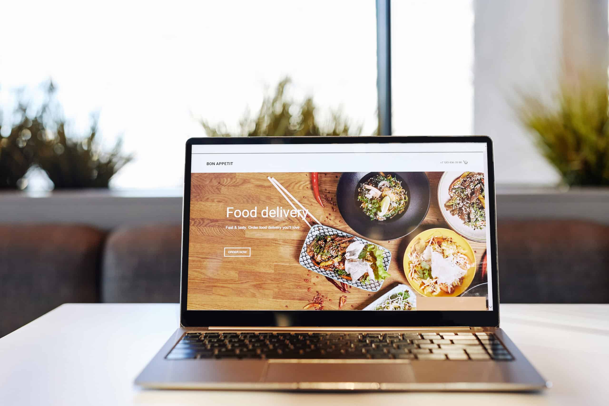 Ein Laptop zeigt eine moderne Website für Food Delivery und Online-Bestellungen. Das Bild symbolisiert digitale Bestellsysteme, Lieferdienste, Restaurant-Websites, Online-Speisekarten und E-Commerce-Lösungen für Gastronomen.